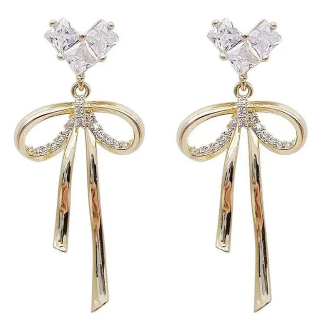 Pair of alloy bow tie ear studs with love heart zircon centre on light background