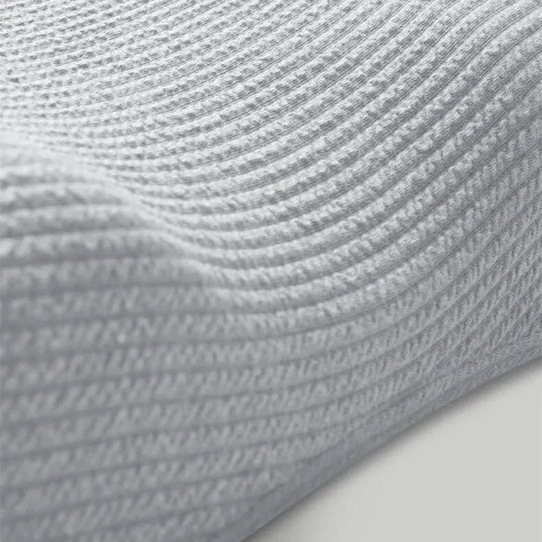 Grey memory foam massage pillow with knitted cotton cover on a bed, offering adjustable neck support for sleep