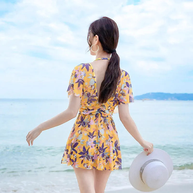 Yellow floral patterned women's one-piece swimsuit on a hanger, showing front design.
