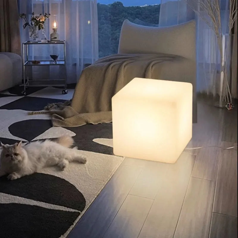Modern square LED cube stool light outdoors, functioning as both a garden seat and a waterproof light source.