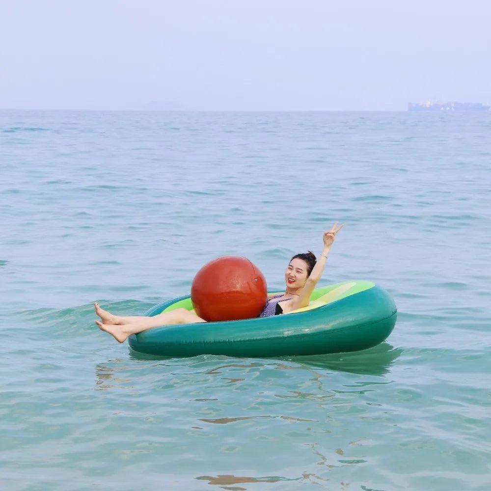Large green inflatable avocado pool float on blue water, showing its 169cm length.