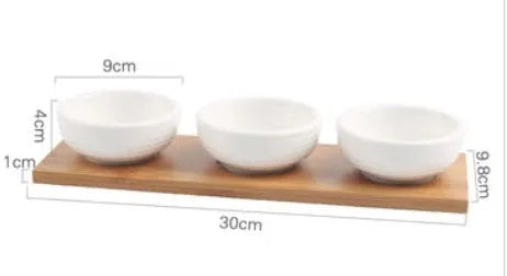 Porcelain ceramic dried fruit dish with three snack compartments on a wooden serving board.