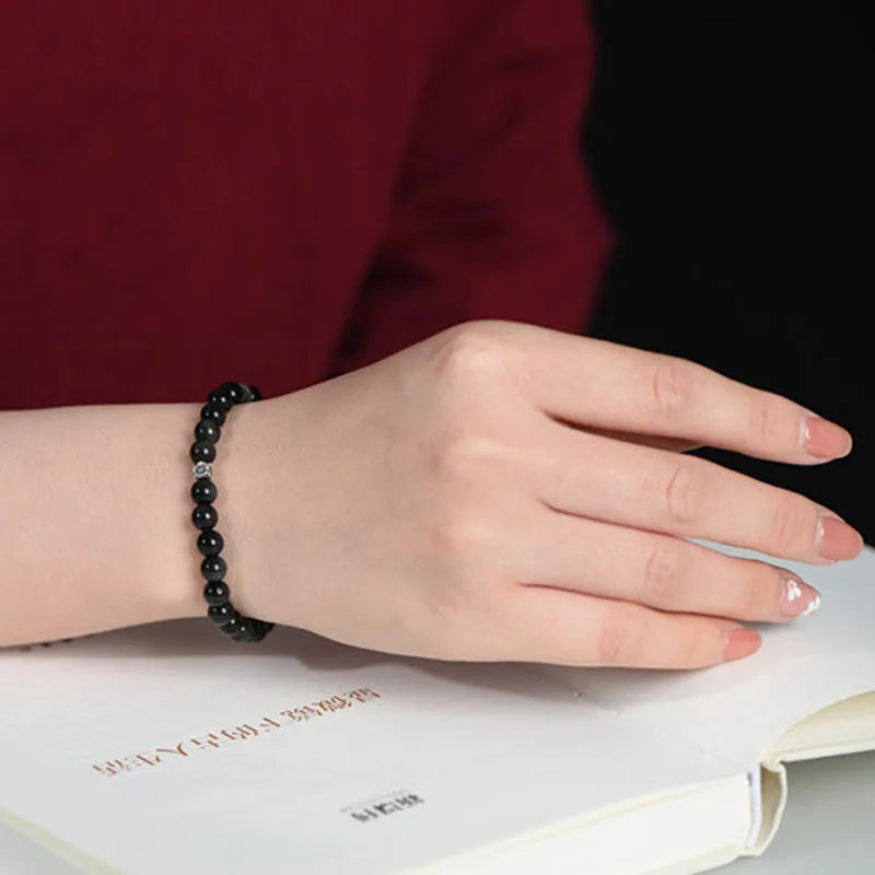 Natural obsidian bracelet with S925 sterling silver flower accessories on a wrist