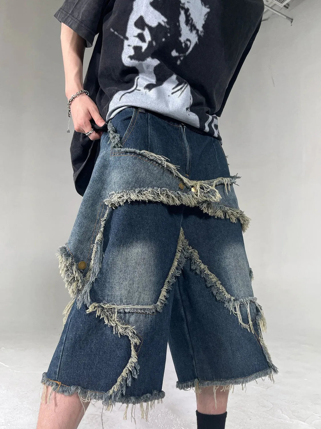 Blue men's loose-fit denim shorts with a frayed five-pointed star design on the leg.