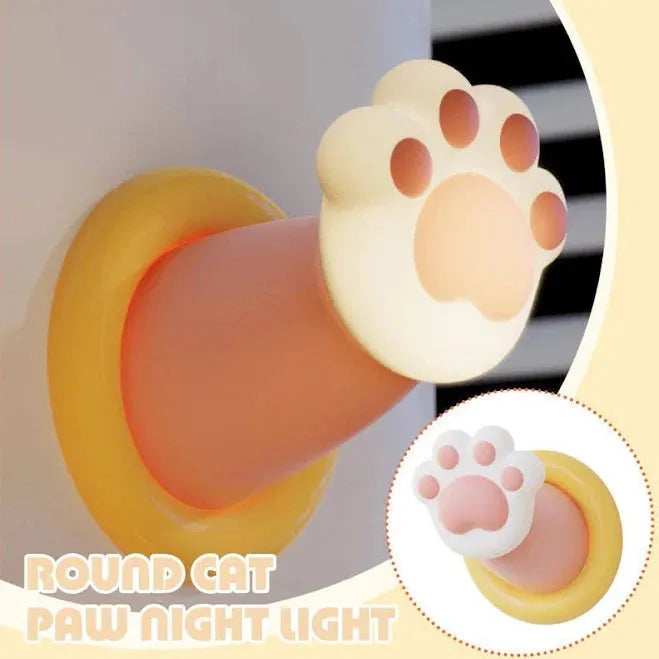 White rechargeable cat paw touch lamp with adhesive back, lit on a bedside table.