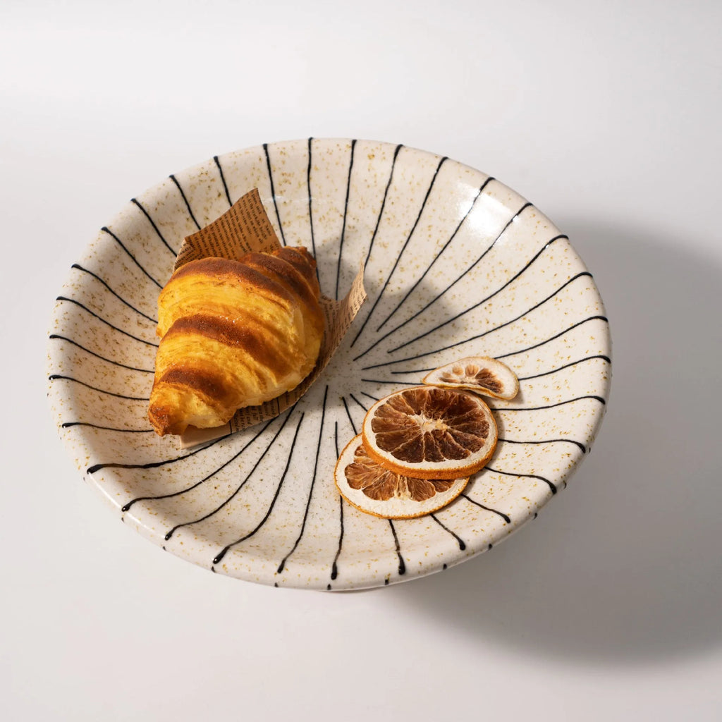 Black and white striped synthetic resin fruit plate on a wooden surface.