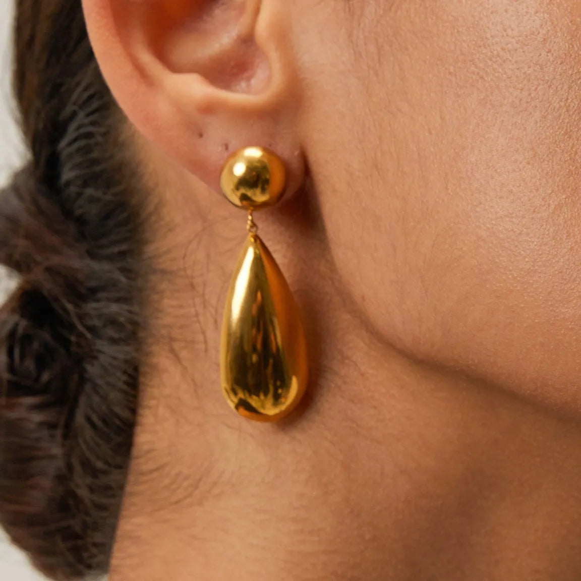 Gold coloured geometric hemisphere earrings with a dangling water drop pendant, made from stainless steel.