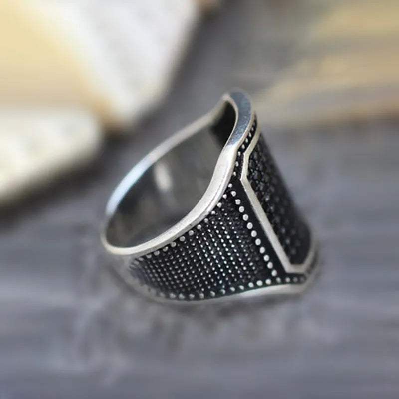 Black alloy ring with copper detailing and a zircon stone, shown in a unisex style.