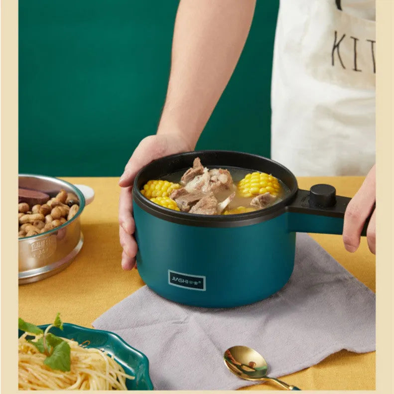 Nordic green mini electric pot with lid and steamer on countertop