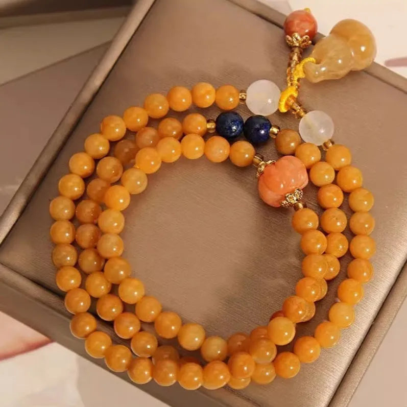 Women's multi-circle bracelet with three strands of natural Jinsi Jade beads and a resin flower calabash pendant on a white background