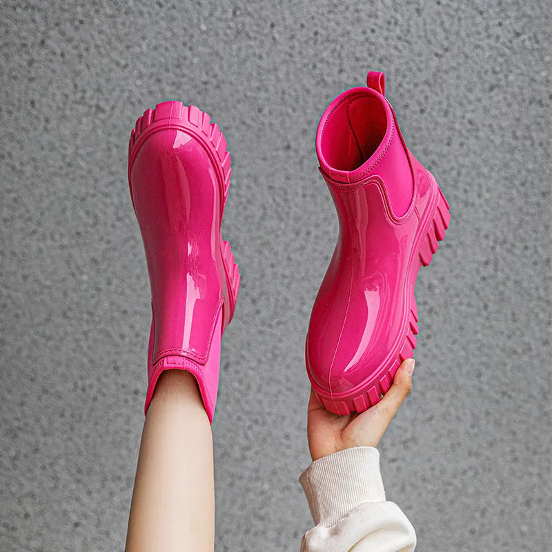 Women's creamy-white PVC rain boots with low tube shaft and flat heel on wet surface