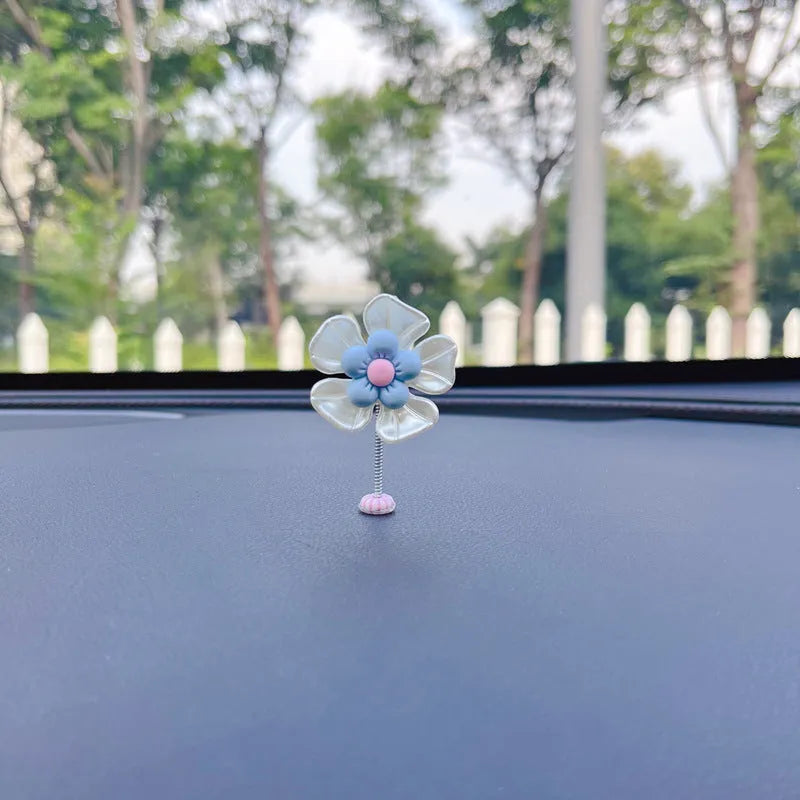 Small blue plastic swing decoration for a car dashboard, shown next to a coin for scale.