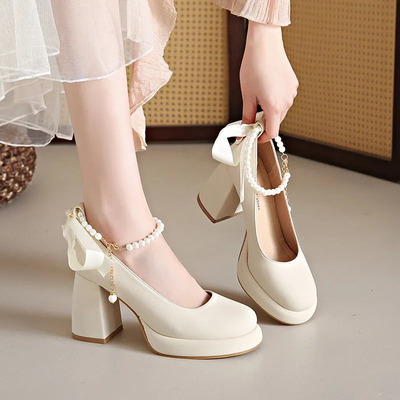 Beige women's Mary Jane shoes with chunky heel, ankle strap, pearl detail, and round toe.