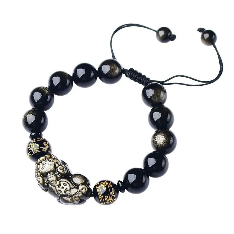 Close-up of a black obsidian bead bracelet with a detailed silver Pi Xiu charm on a neutral background.
