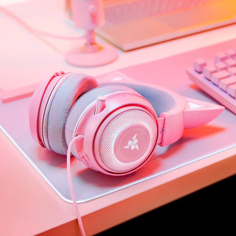 Pink glowing cat earphones with wired USB connection and head-mounted design on a desk