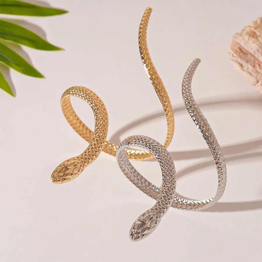 Gold exaggerated twisted winding open snake ring and bracelet jewellery set on white background.