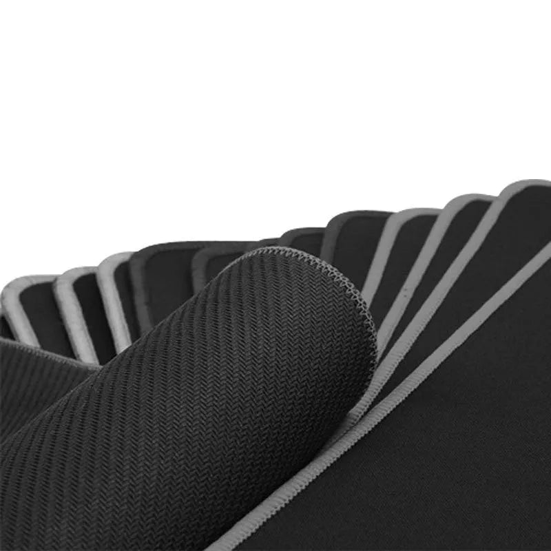 All black extended large desk mat with overlock stitching for keyboard and mouse on a wooden desk.