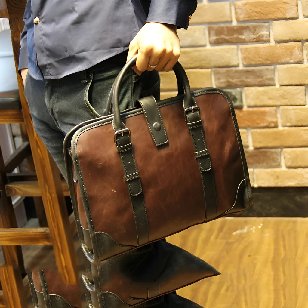 Men's cowhide leather brown business messenger bag with zip closure and shoulder strap on a wooden table