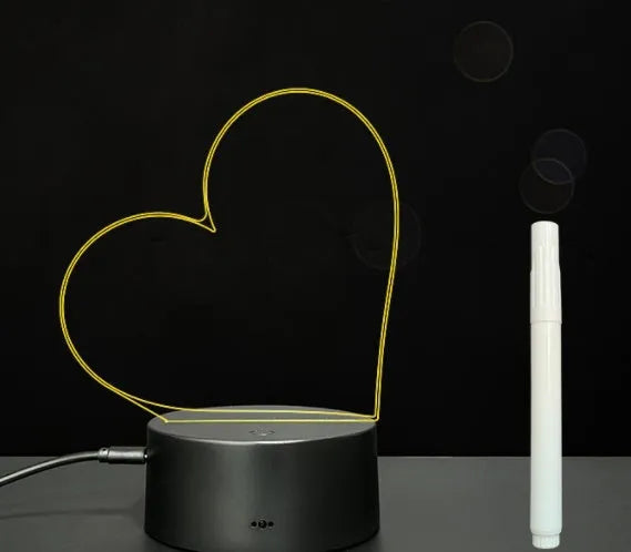3D acrylic message board night light with remote control and stylus on a desk.
