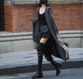 Long grey knitted cardigan with a hood, shown on a model, featuring a loose trench coat style.
