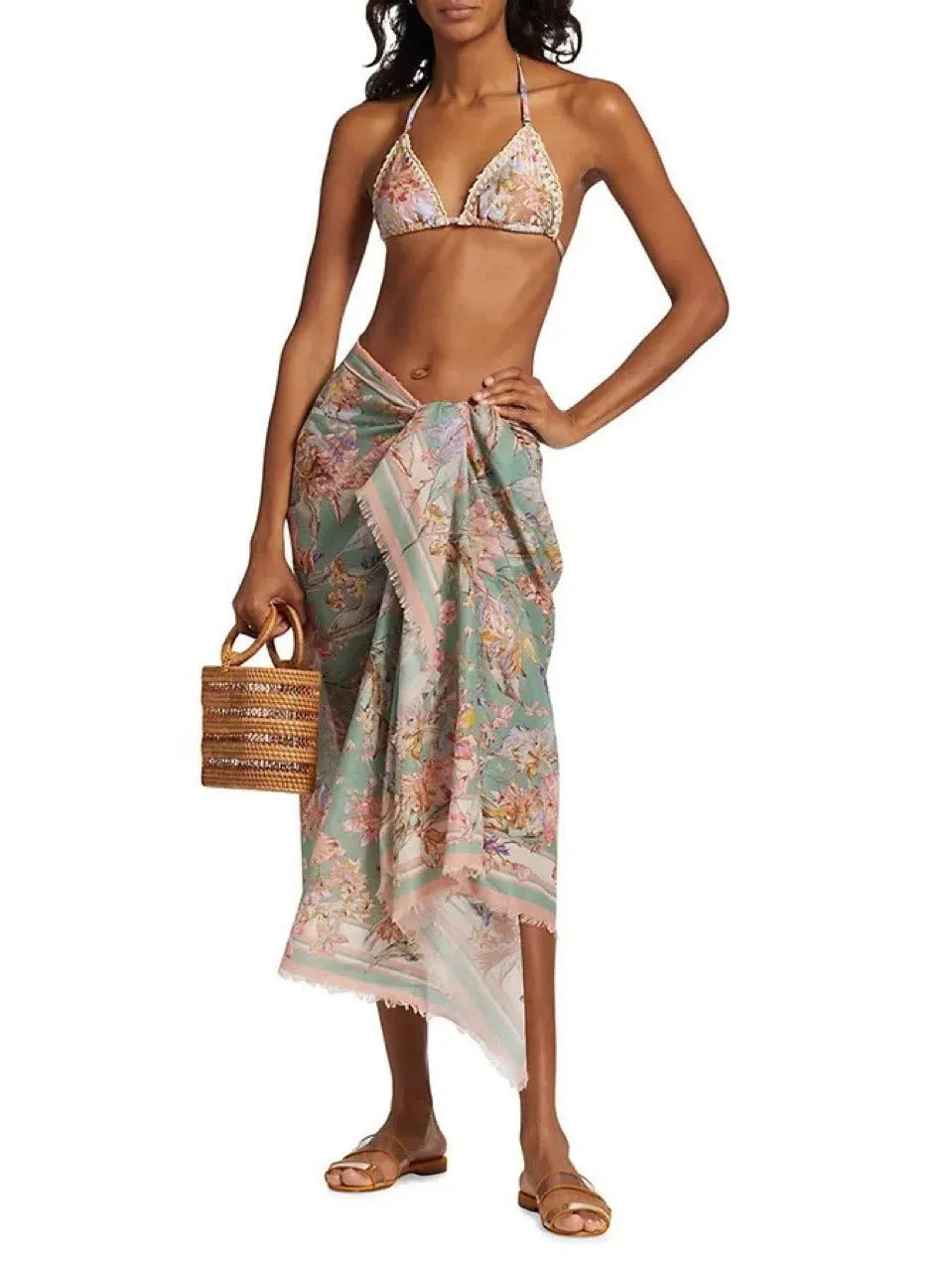 Women's creamy-white floral bikini swimsuit set with matching skirt on beach
