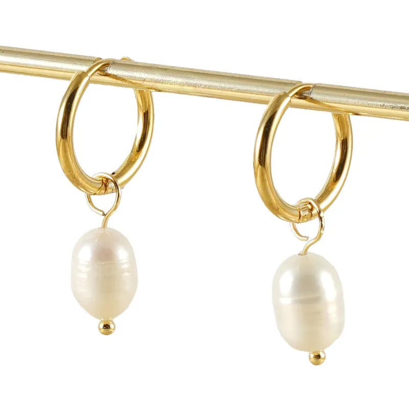 Geometric gold-coloured stainless steel earrings with a white pearl detail on a white background.
