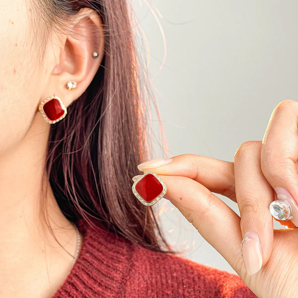 Red alloy square earrings with an inlaid geometric pattern, shown from the front.