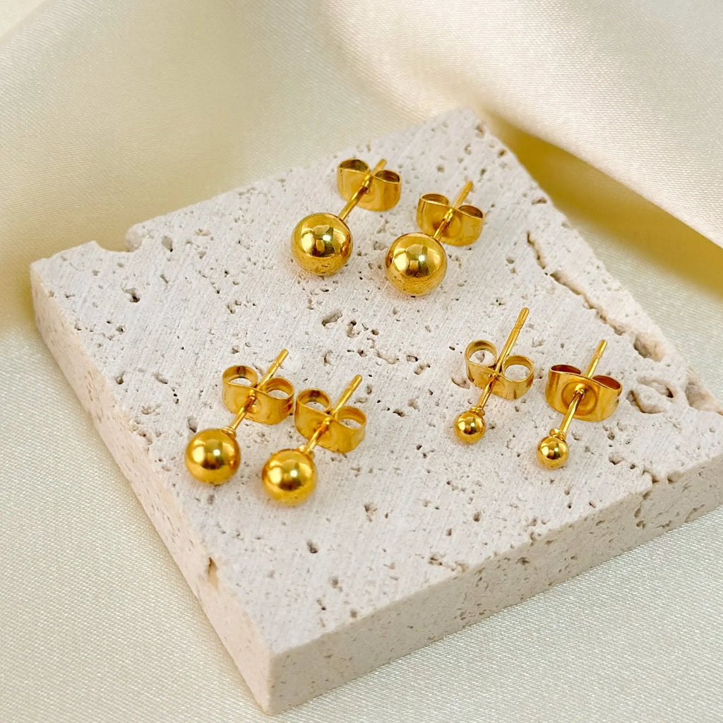Titanium steel 18K gold electroplated ball stud earrings in round geometric design on white background.