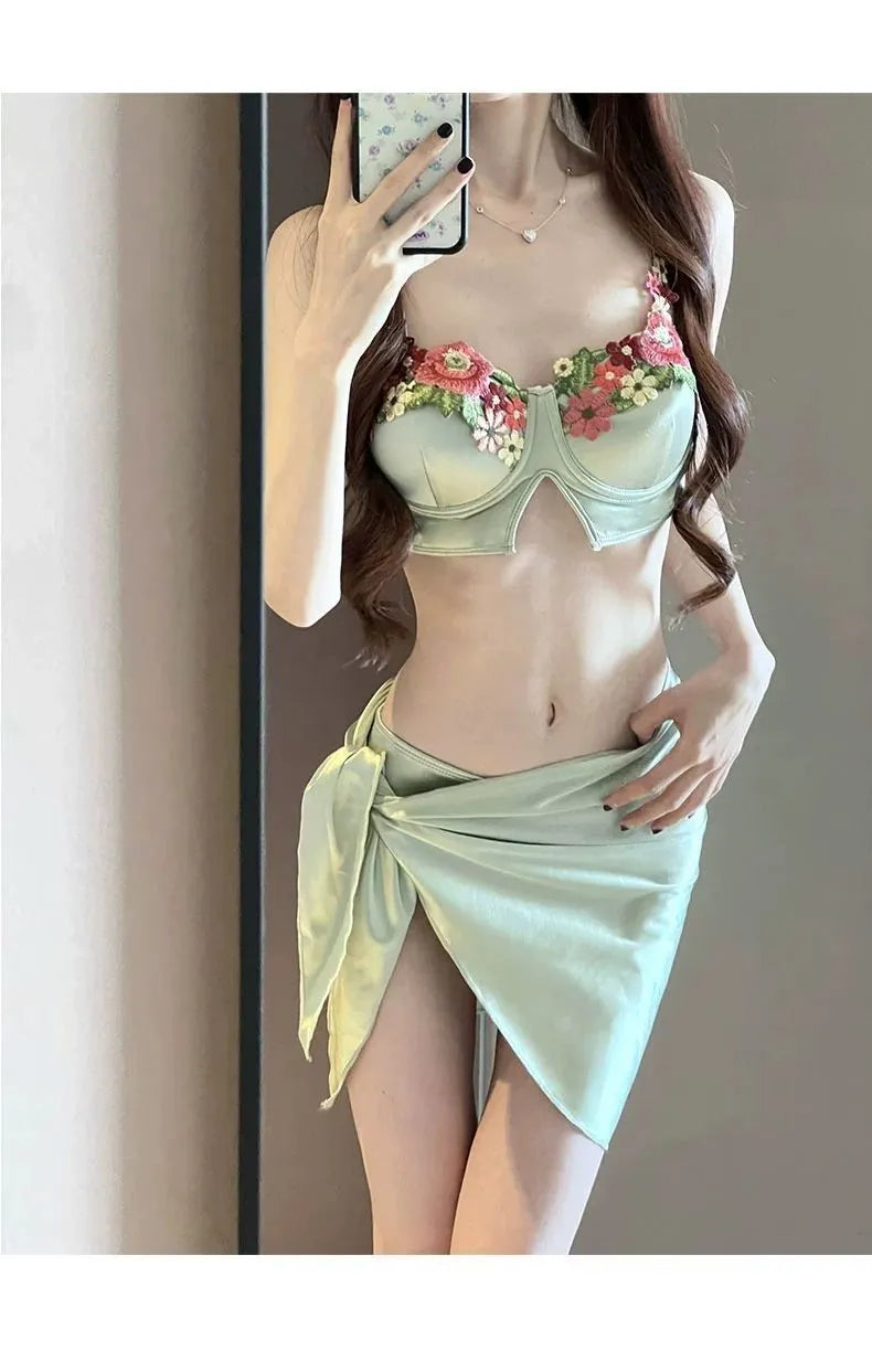 Green women's three-piece bikini set with triangle cup top, briefs, and skirt cover-up