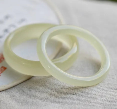 Ice-like silk jade round bar bracelet showing geometric winding design on a wrist.
