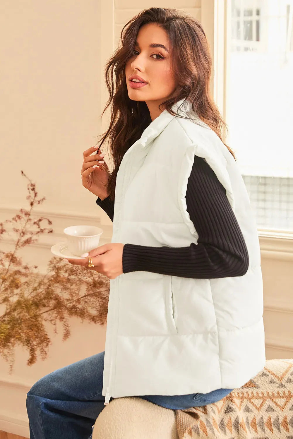 Women's beige oversized puffer vest with stand neck and front zipper, made from polyester, shown on a model