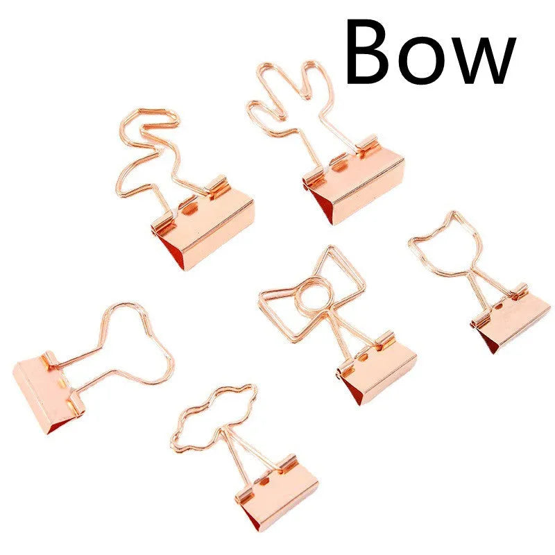 Small gold metal paper clip with a decorative bow charm attached.