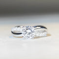 Silver geometric cross ring with a 1 karat moissanite stone in a twisted four-claw setting