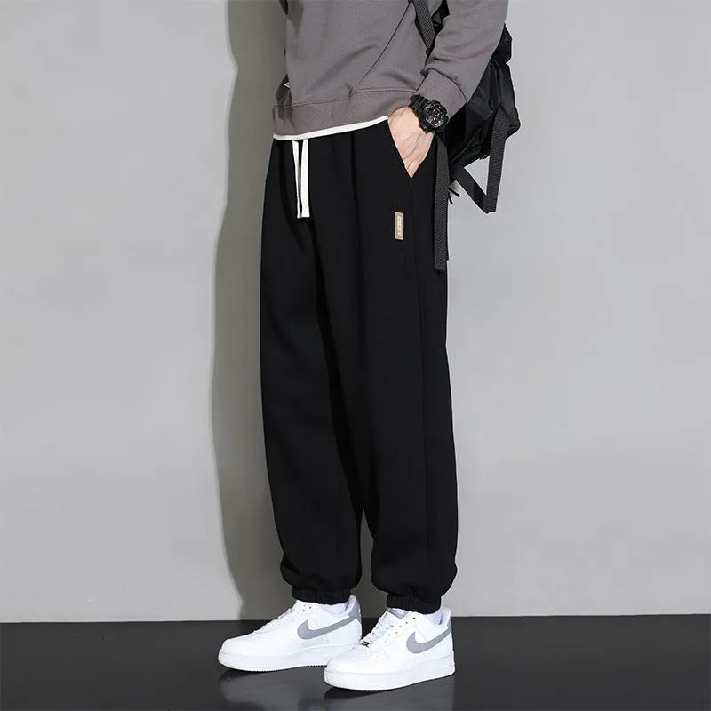 Men's grey loose-fit cotton blend sports trousers with a drawstring waistband on a hanger.