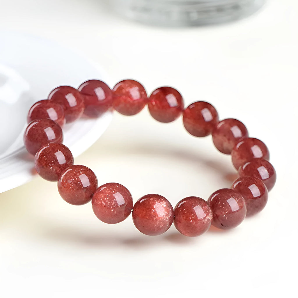 Natural cherry red strawberry quartz bracelet with geometric beads on a wrist.