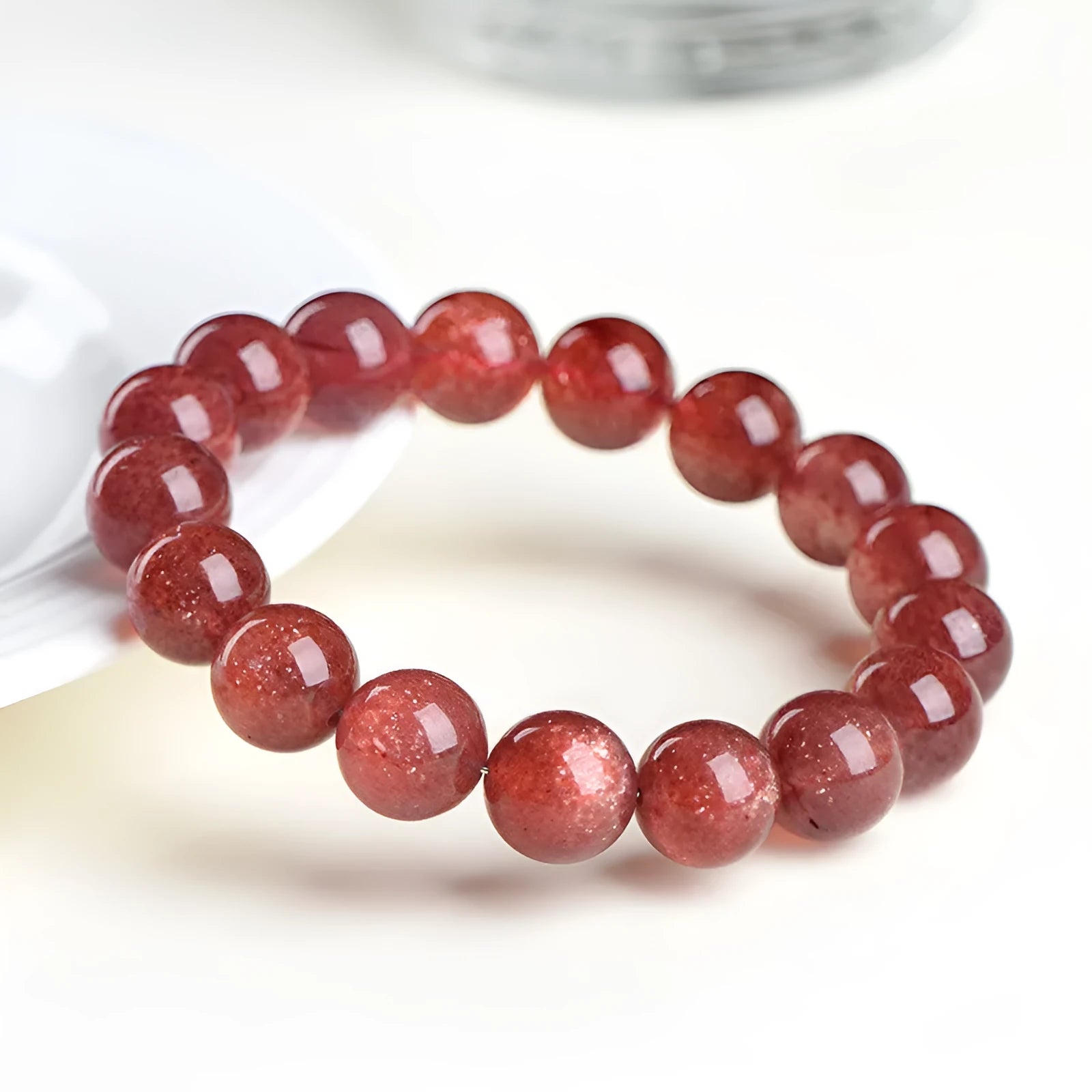 Natural cherry red strawberry quartz bracelet with geometric beads on a wrist.