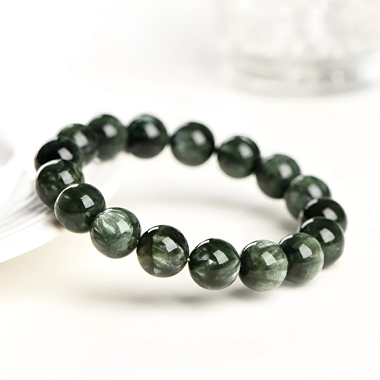 Green dragon crystal bracelet with round beads and a ruyi charm on a wrist.