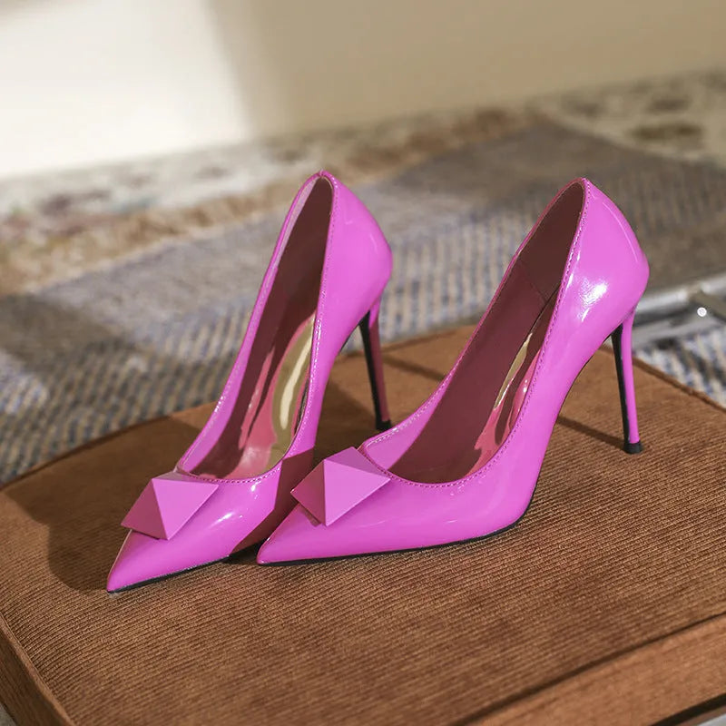 Pink women's patent leather stiletto high heels with a buckle and pointed toe.