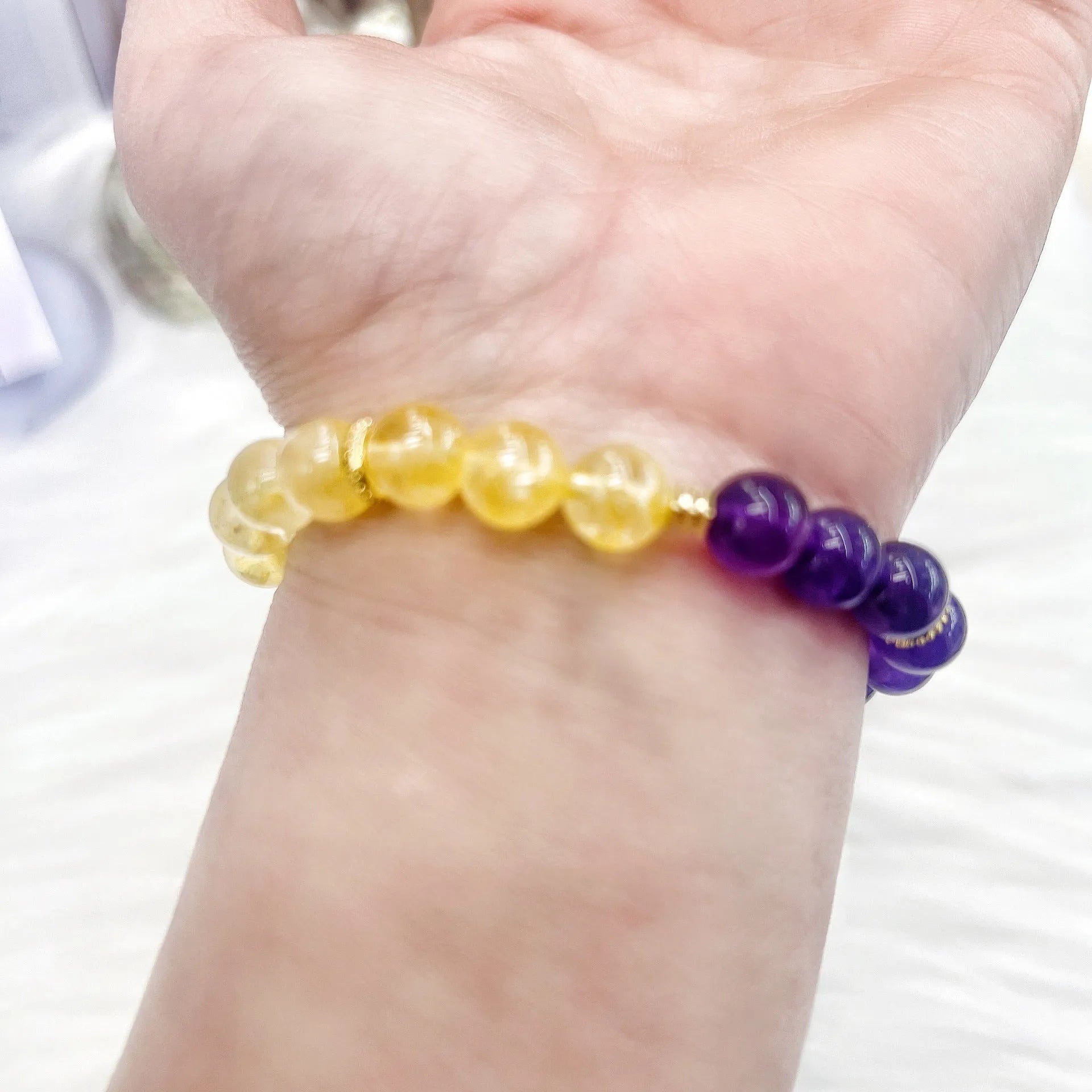 Handmade women's yellow and purple amethyst crystal bracelet showing manual craftsmanship detail