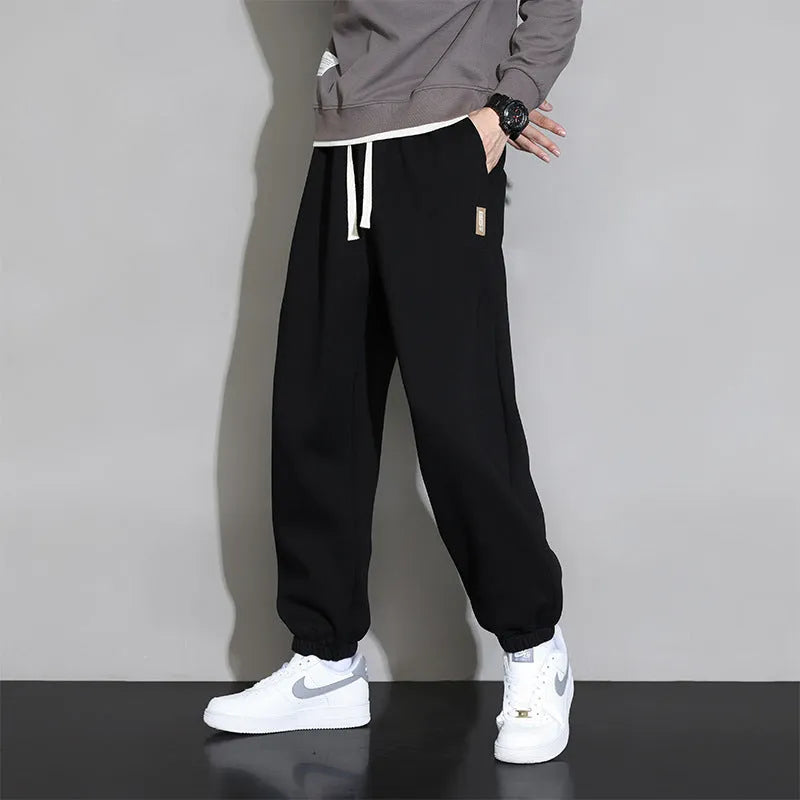 Men's grey loose-fit cotton blend sports trousers with a drawstring waistband on a hanger.