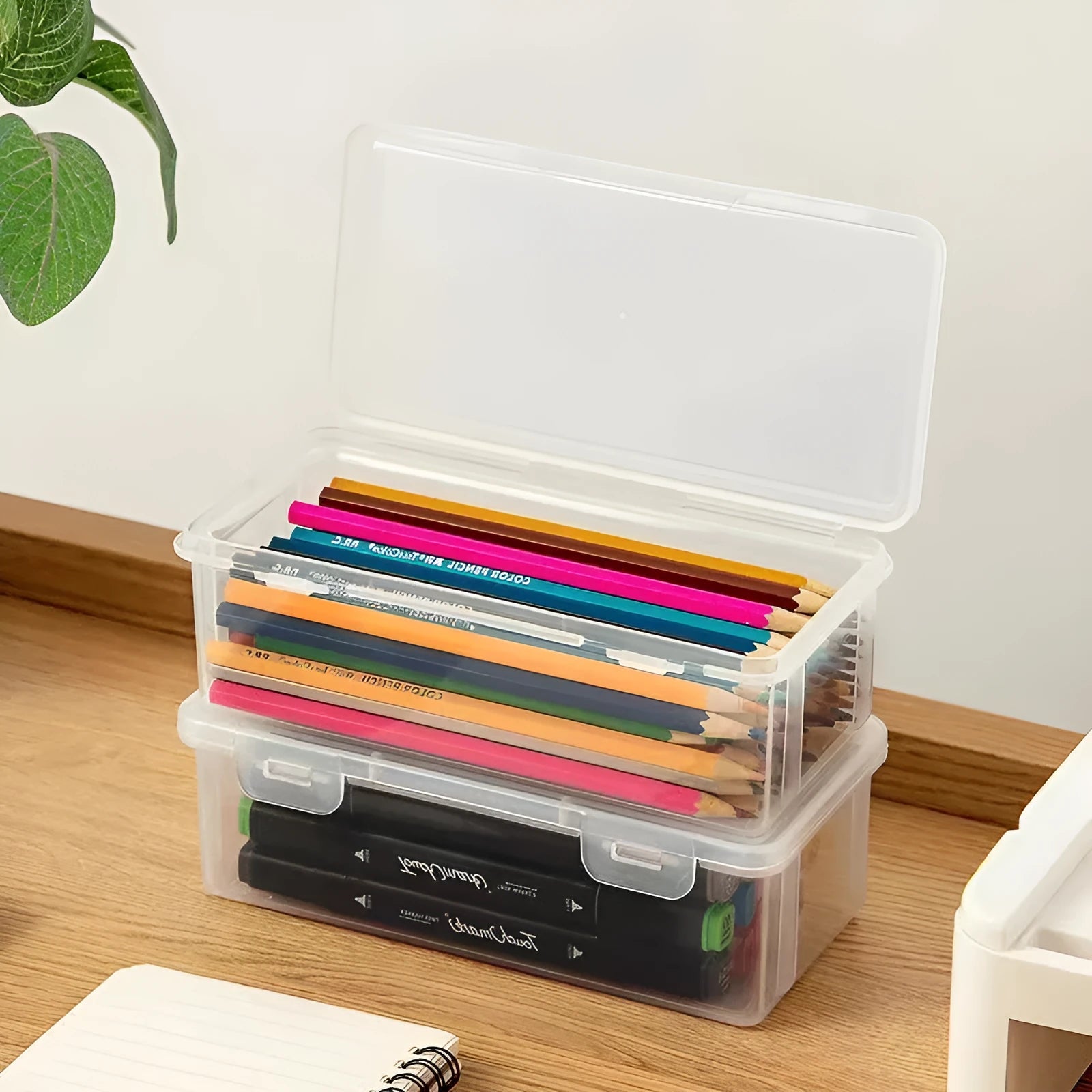Clear plastic pencil storage box filled with colouring pencils and wax crayons.