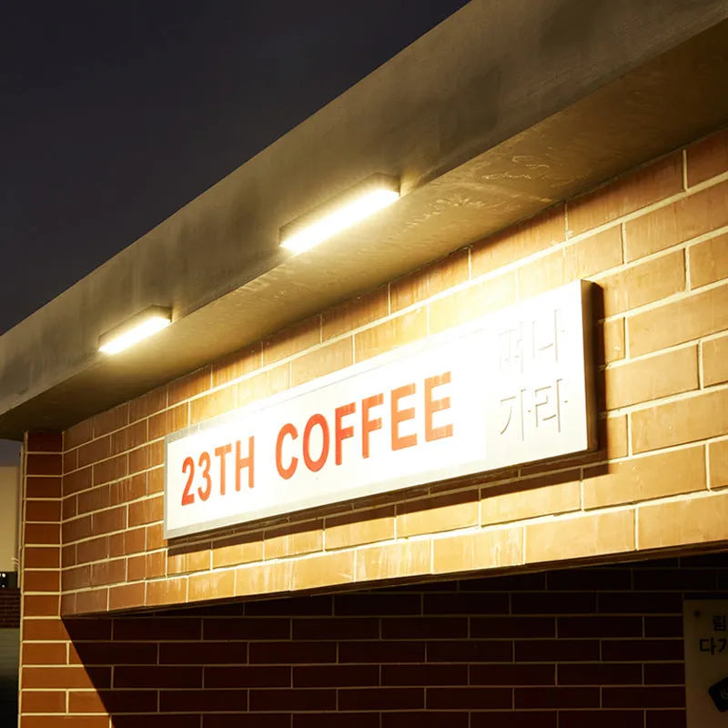 Black solar-powered outdoor wall lamp with solar strip, suitable for garden or yard.