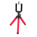 Mini flexible black sponge octopus tripod stand holding a smartphone on a desk edge.