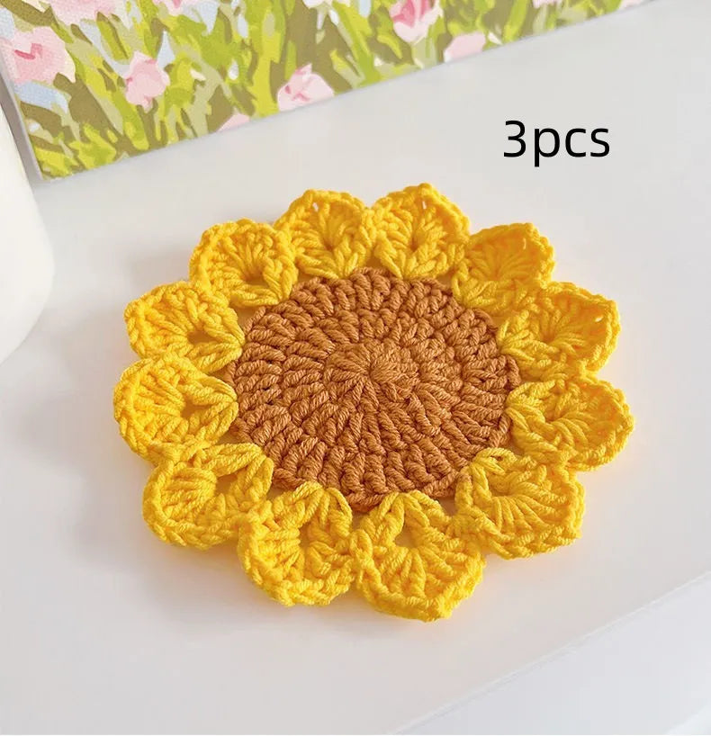 A hand-woven circular wool coaster with a floral pattern, shown as a single piece.