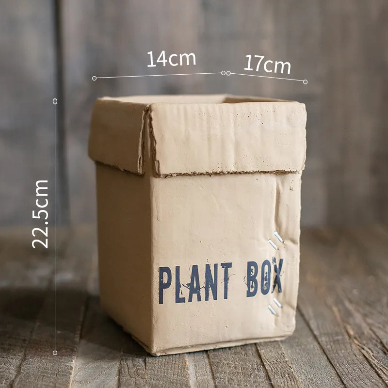 Cement flowerpot with brown paper carton design and drainage hole for indoor balcony plants.