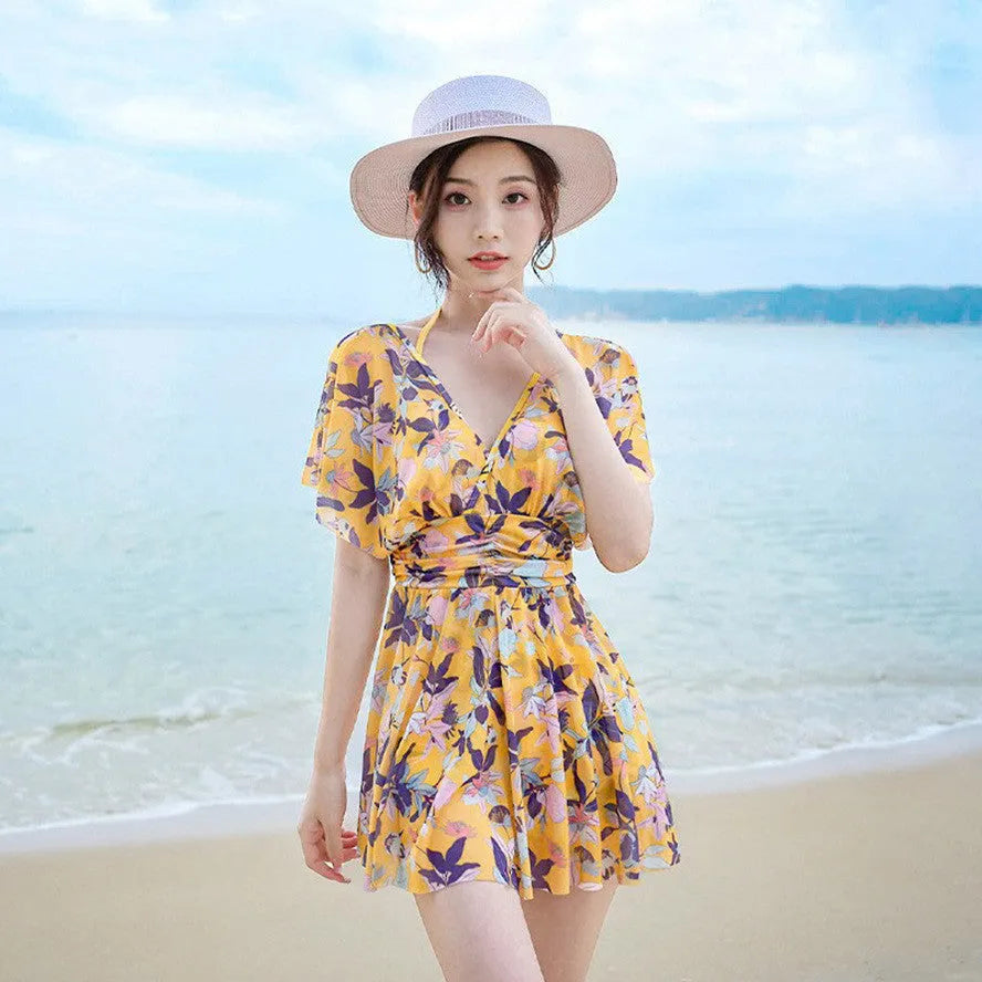 Yellow floral patterned women's one-piece swimsuit on a hanger, showing front design.