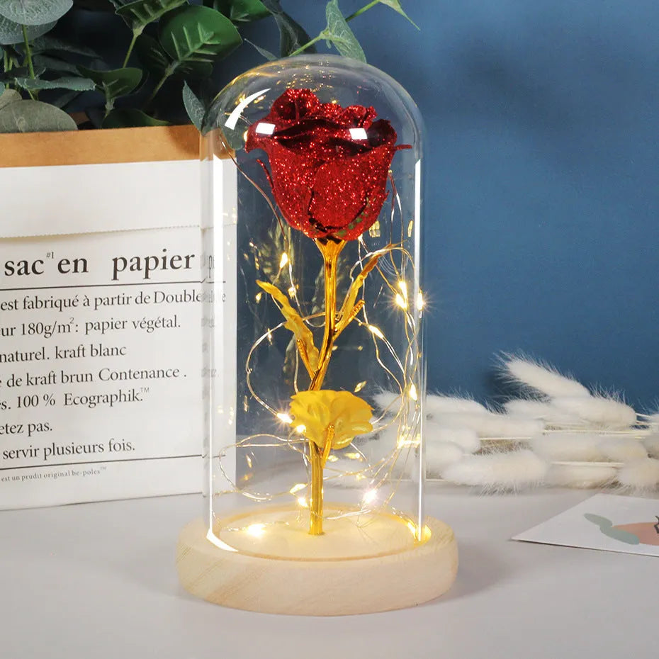 Glass dome containing red eternal roses illuminated by a warm white bendable LED light string.