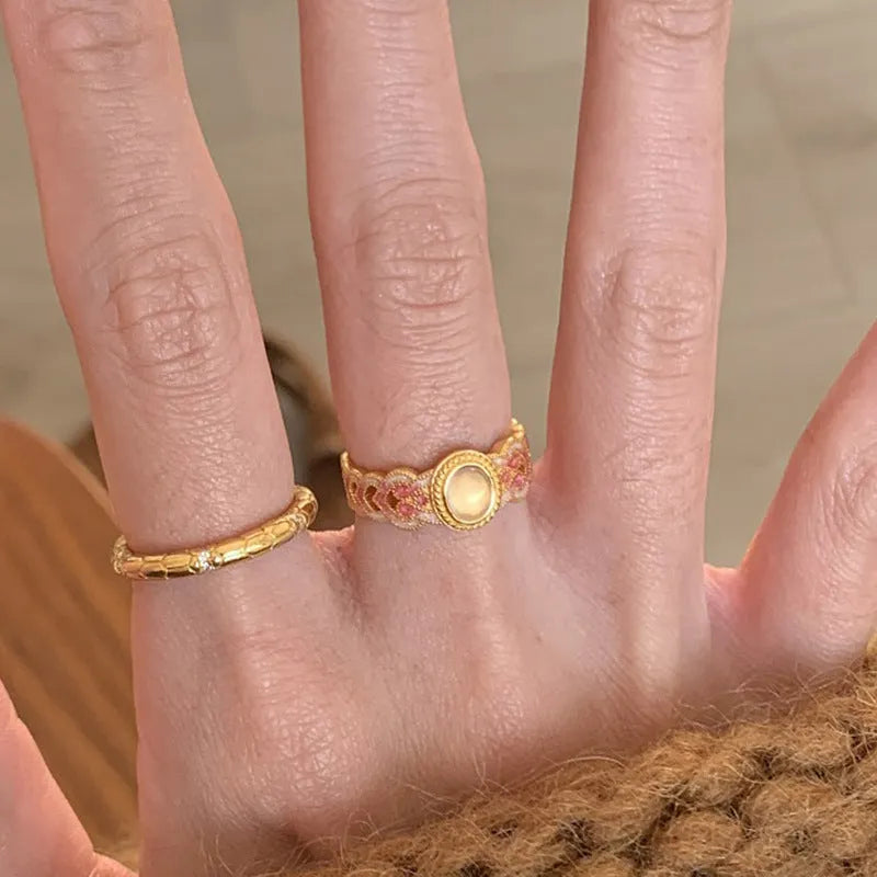 Gold geometric open ring with a pink crystal enamel stone on a model's finger.