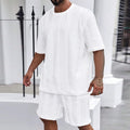 Knitted solid colour short sleeve pullover and matching shorts laid flat.