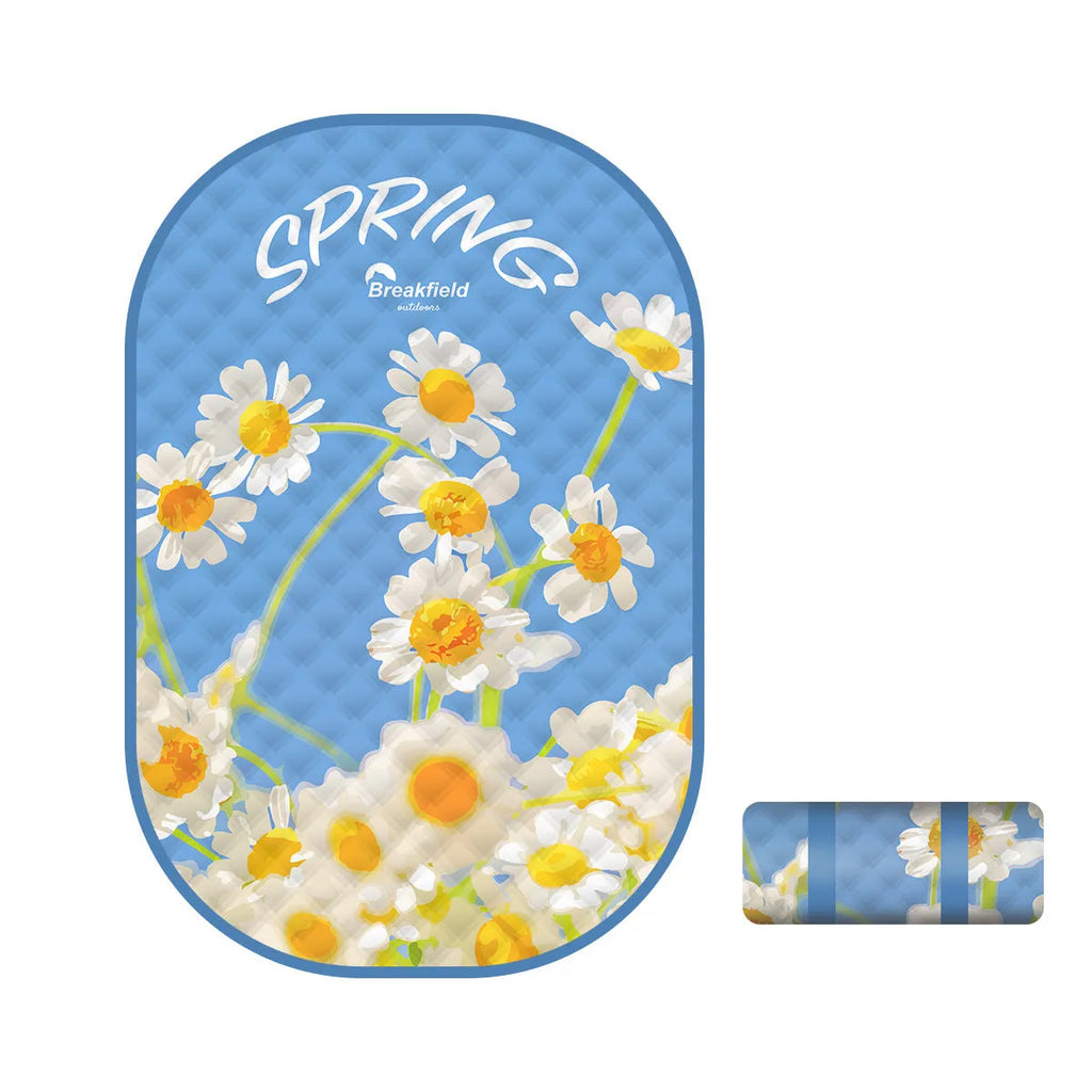 A large rectangular waterproof picnic mat in a seasonal colour, laid out on grass for a group.